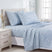 Light blue bedding set with a white floral pattern, including a sheet, two pillowcases, and a folded blanket, styled on a bed in a bright bedroom. #color_classic-meadow-blue