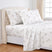 White bed sheet set with a dandelion print, shown on a bed with matching pillowcases and a duvet cover, styled in a bright bedroom with a tufted headboard. #color_dreamseed-taupe