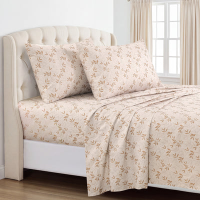 A neatly made bed with a cream sheet set featuring a delicate tan leaf pattern, styled with matching pillowcases and a tufted cream headboard in a bright bedroom. #color_willow-grove-rust