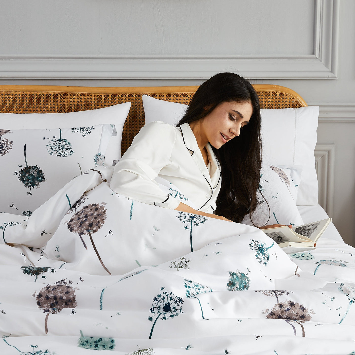 Lady reading a book on bed with Dandelion Dreams Duvet Cover in White#color_dandelion-white