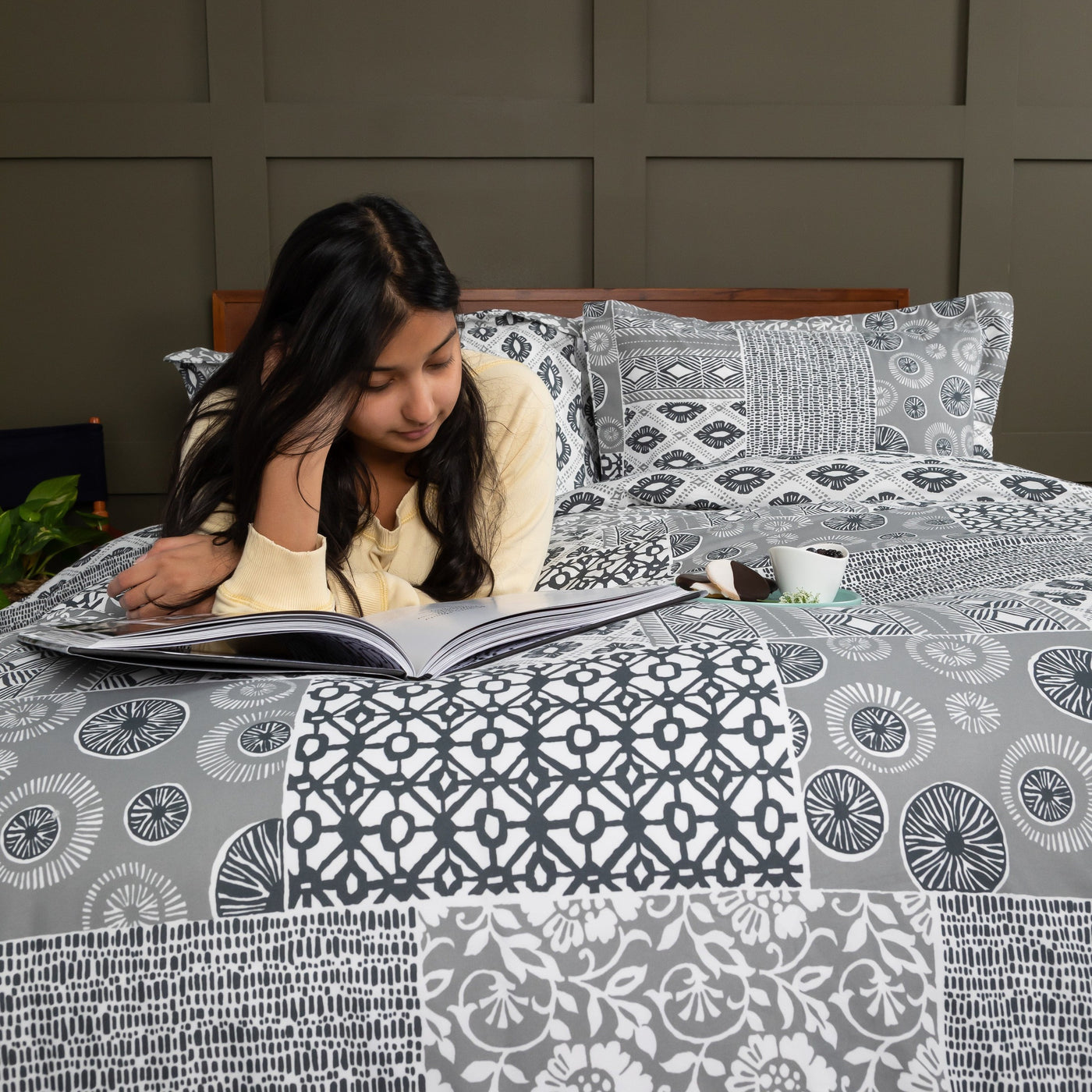 Lady Reading a book on a Global Patchwork Duvet Cover Set in Grey#color_patchwork-grey