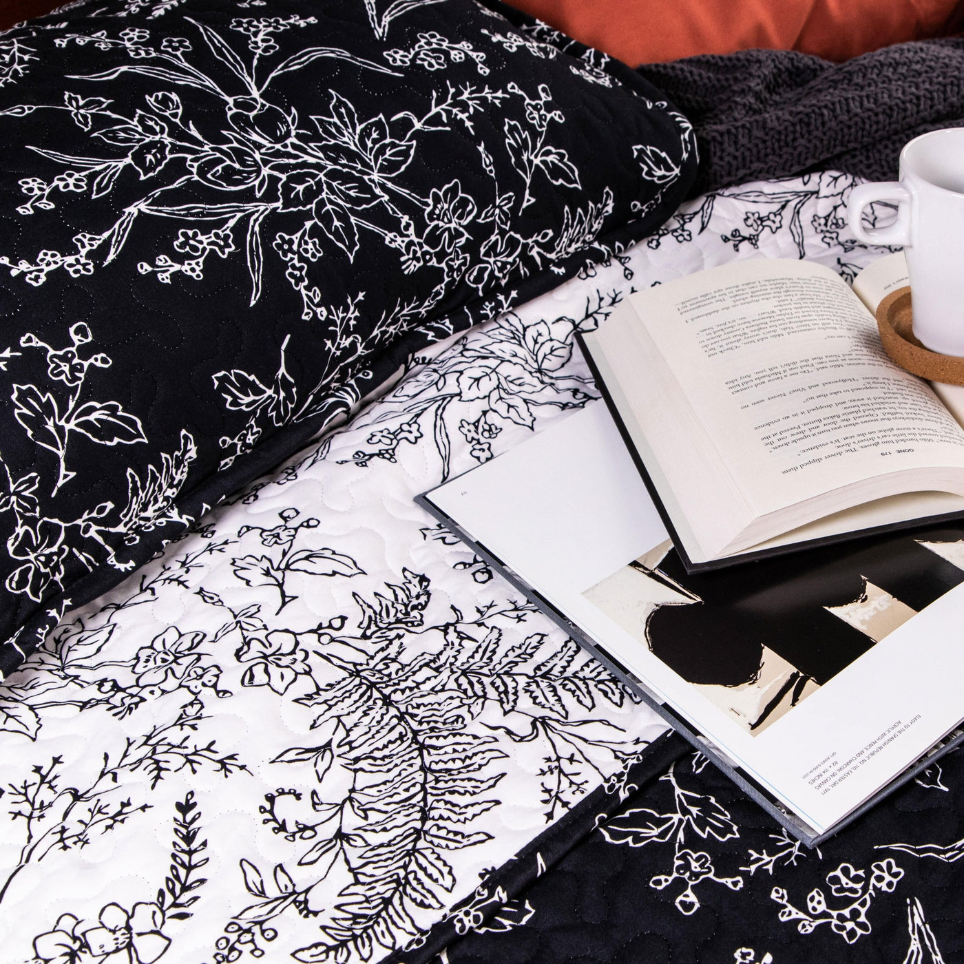 Books and coffee on top of Winter Brush Reversible Quilt Set in Black#color_winter-brush-black