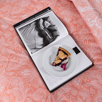 Magazine and plate of pie on Perfect Paisley Reversible Comforter Set in Coral#color_perfect-paisley-coral-haze