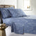 Angled view of Modern Foliage sheet set showcasing blue sheets with white leaf print on a made bed with wooden headboard