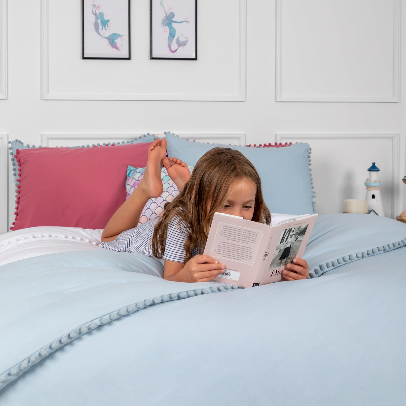 Child reading a book on bed with Pom-Pom Duvet Cover Set in Blue#color_light-blue