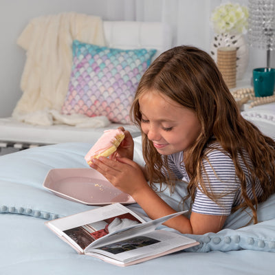Child eating a snack and reading on bed with Pom-Pom Duvet Cover Set in Blue#color_light-blue